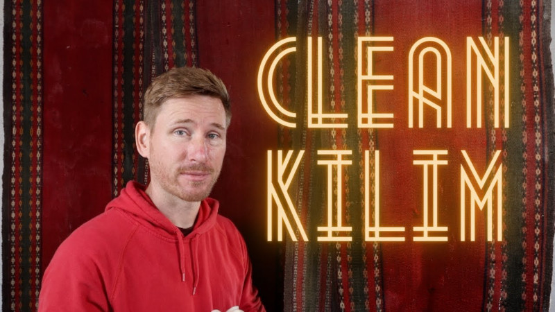 man standing next to kilim rug with neon type sign